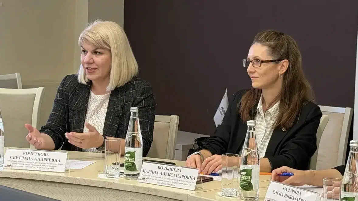 Две женщины за столом обсуждают вопросы во время деловой встречи.
