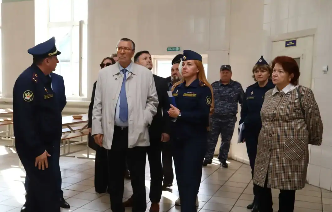 Сотрудники в форме и посетители осматривают помещение с рядами столов.