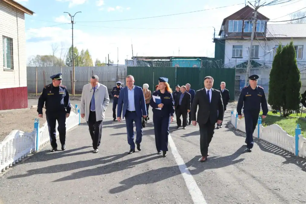Группа сотрудников и посетителей идет по территории учреждения.
