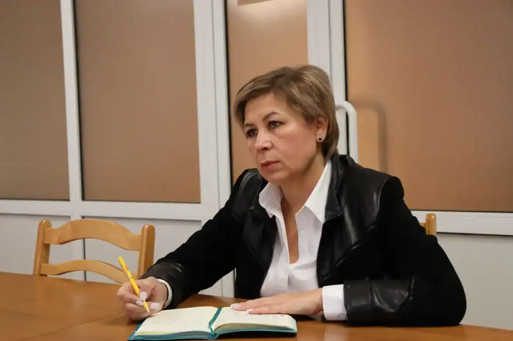 Женщина делает записи в блокноте за столом в кабинете.