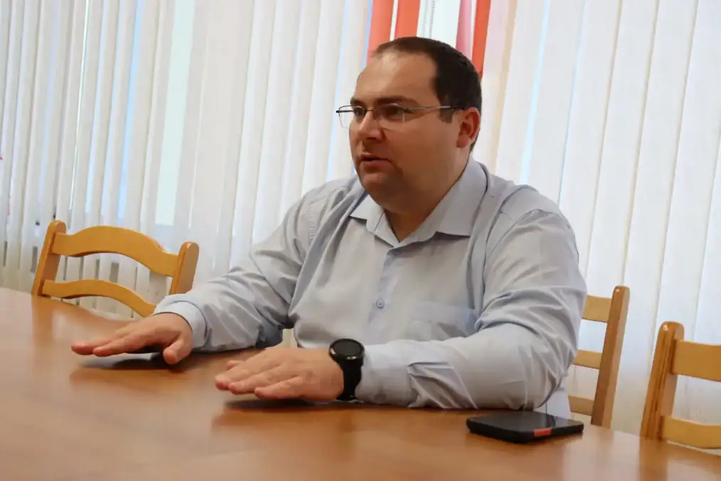 Мужчина в рубашке сидит за столом во время разговора.