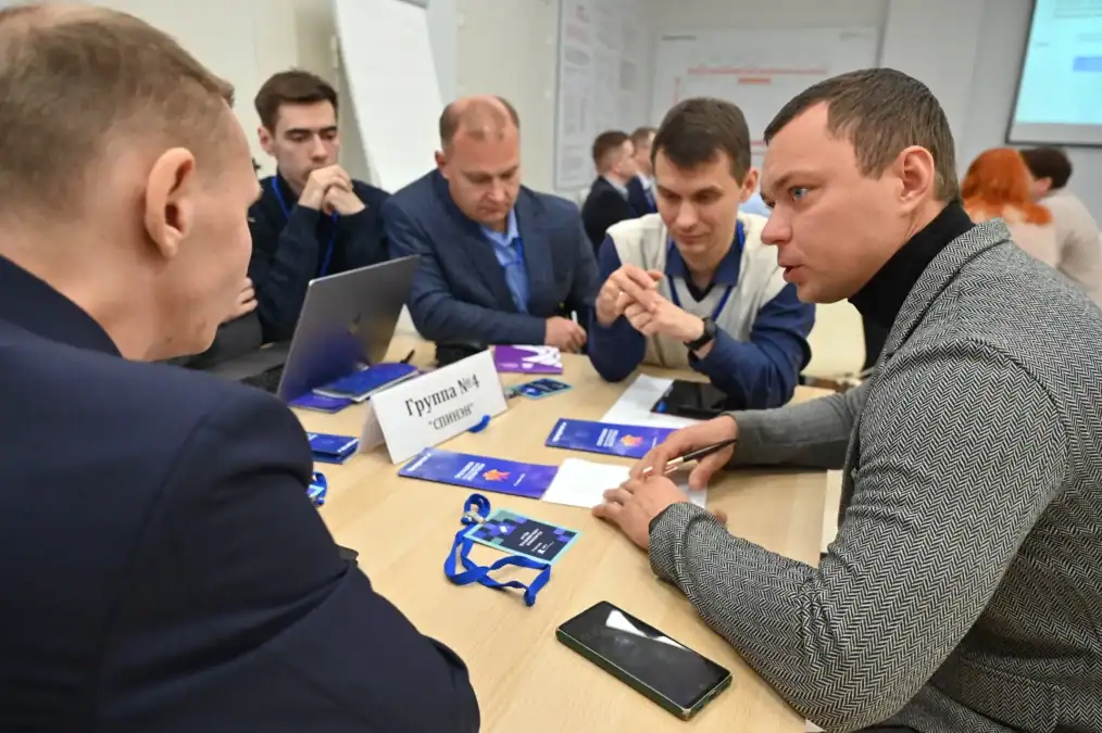 Мужчины обсуждают материалы рабочей группы за столом.