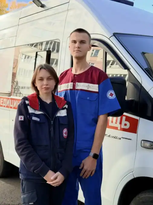Двое сотрудников скорой помощи стоят у автомобиля СМП.