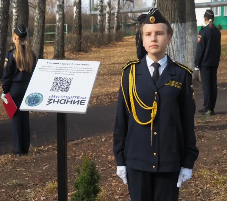 Кадет стоит рядом с информационным стендом с QR-кодом.