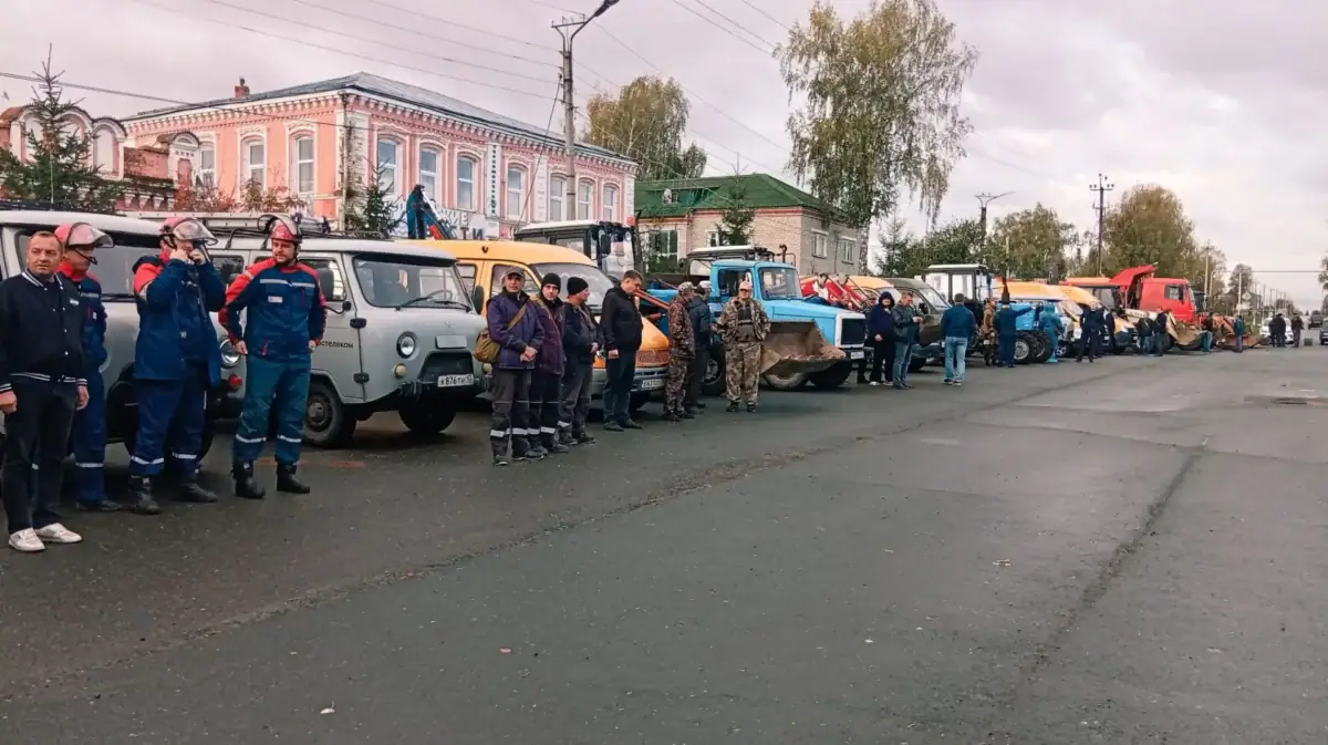 Спецтехника и сотрудники служб выстроены вдоль городской улицы.
