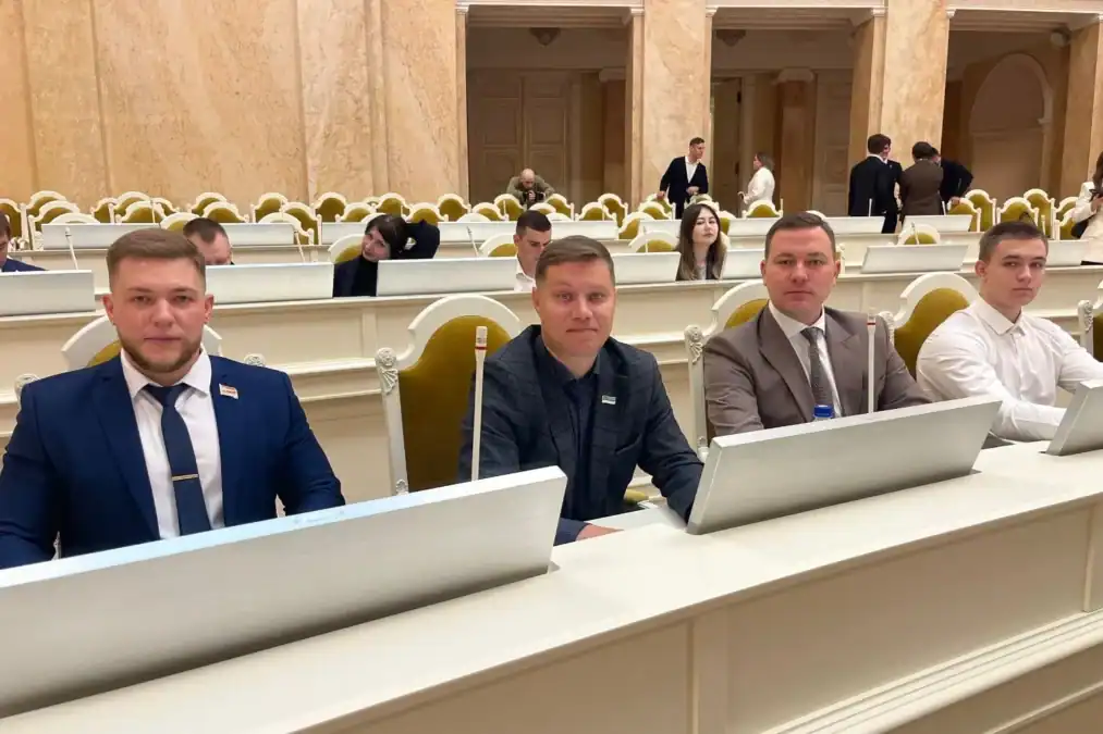 Четверо мужчин сидят за столом в зале заседаний.