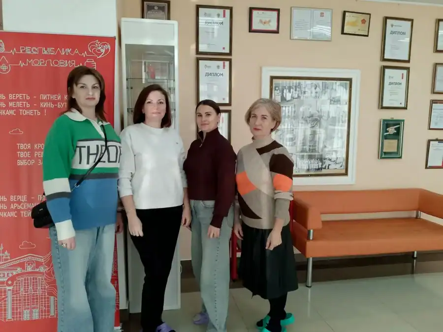 Четыре женщины с повязками на руках стоят в помещении службы крови.