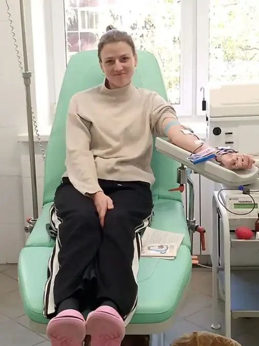 Женщина сидит в донорском кресле с подключённой к руке системой.