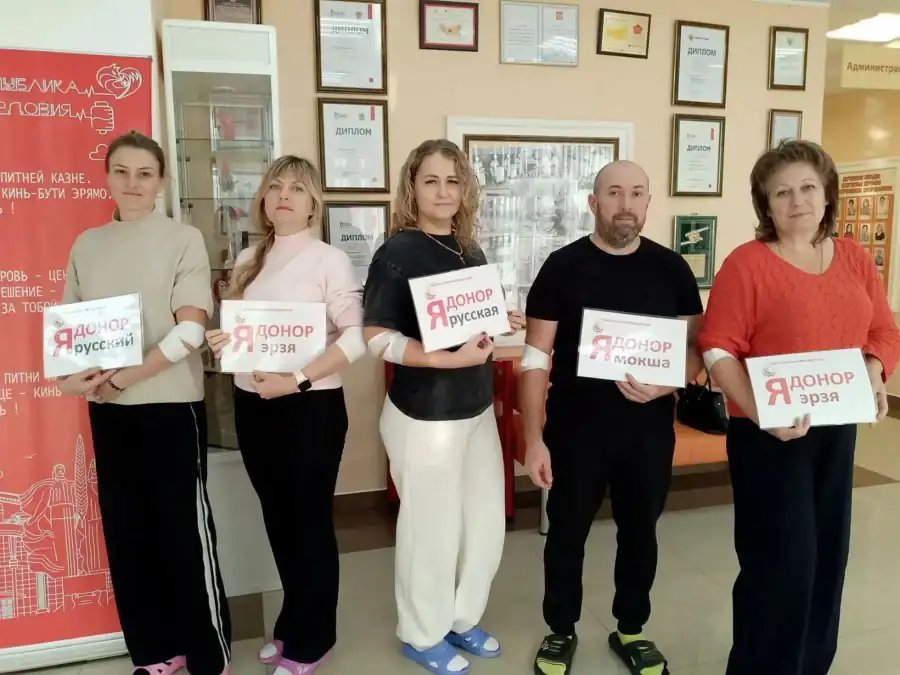 Пять участников акции с повязками на руках держат таблички «Я донор».
