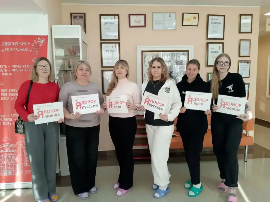 Шесть участниц акции держат таблички «Я донор» в холле.