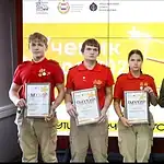 Четверо школьников с дипломами стоят рядом с мужчиной в костюме.