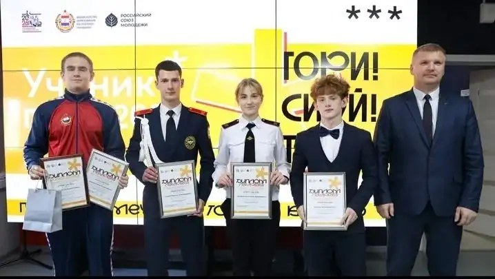 Четверо участников с дипломами стоят рядом с мужчиной в костюме.