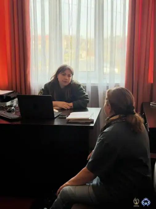 Женщина за столом с ноутбуком беседует с посетительницей.