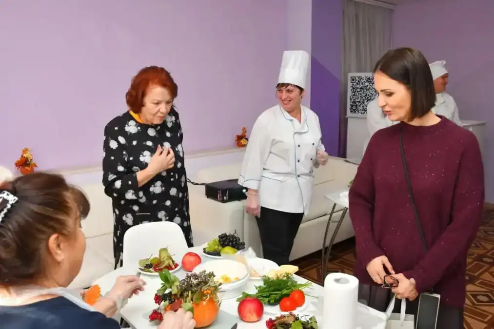 Женщины осматривают блюда на столе рядом с поварами.