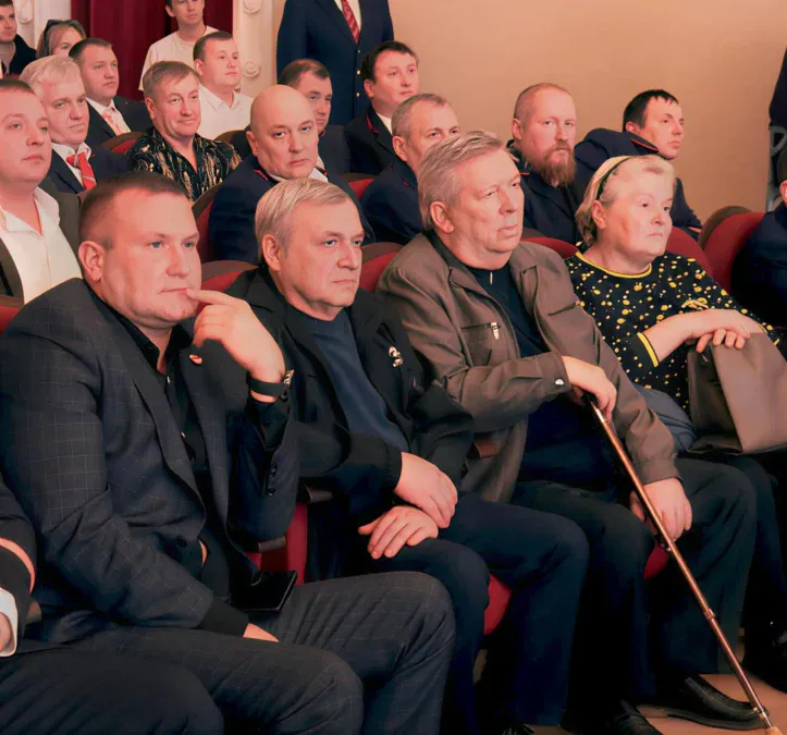 Зрители и ветераны сидят в зале во время мероприятия.