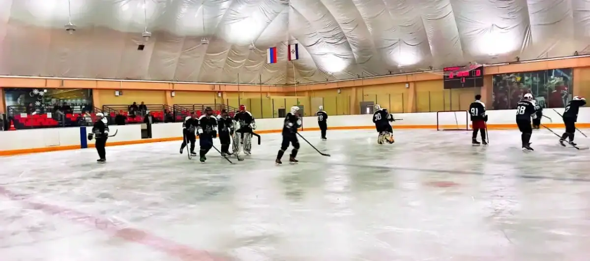 Хоккеисты играют у ворот на крытой ледовой площадке.