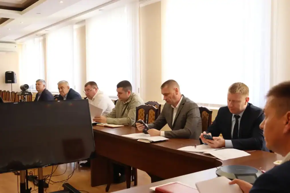 Участники заседания сидят за столом с документами в конференц-зале.