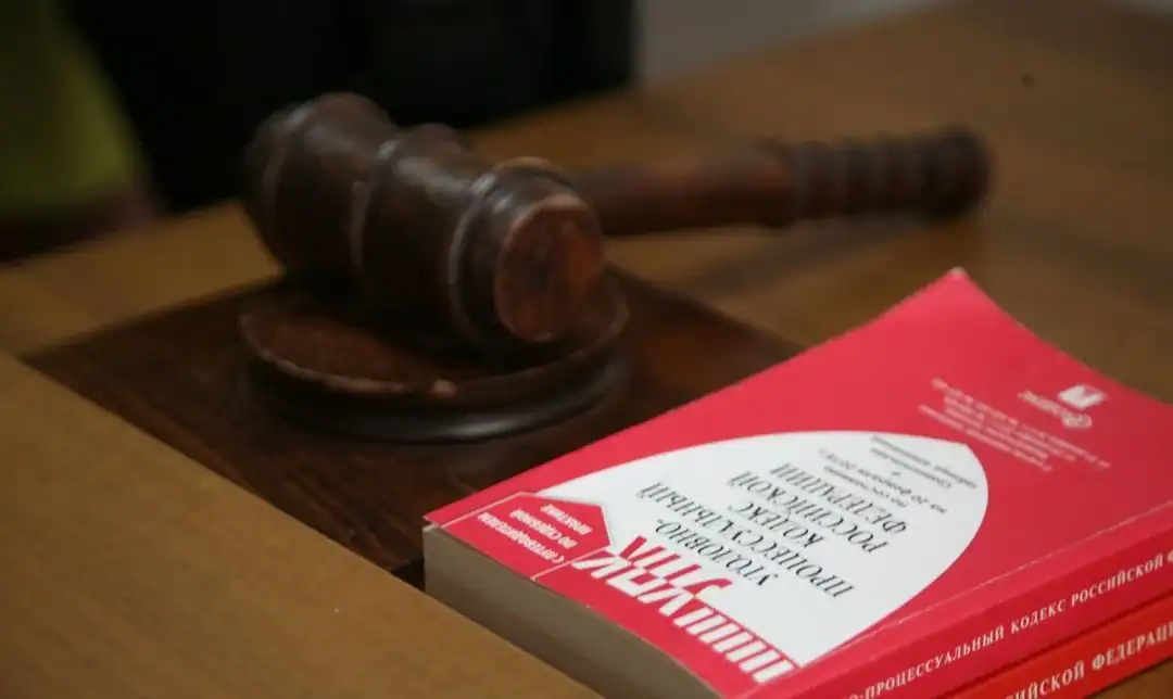 Судейский молоток лежит рядом с книгой Уголовного кодекса России.