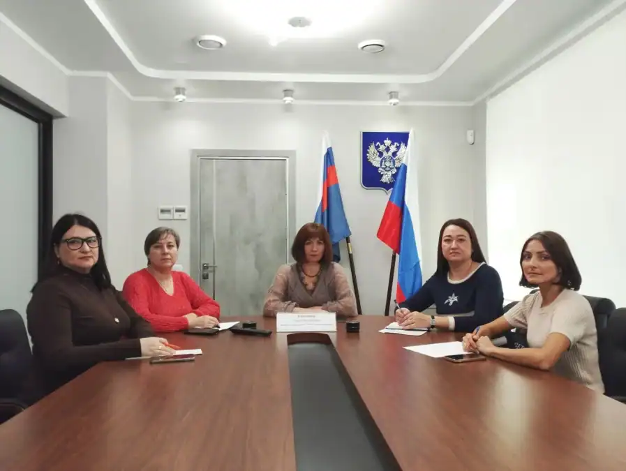 Пять женщин участвуют в совещании за длинным столом в кабинете.