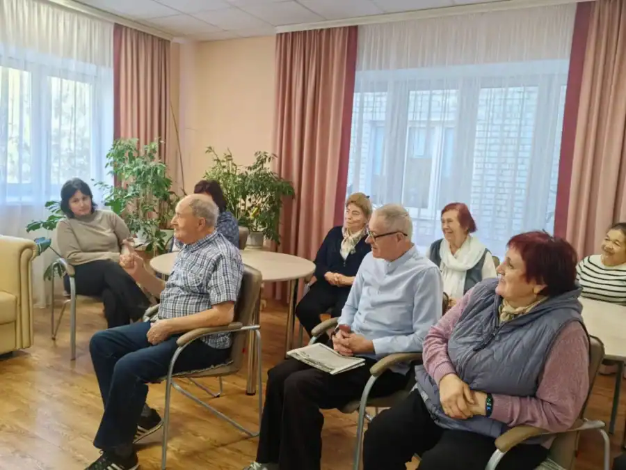 Посетители центра сидят в комнате и беседуют друг с другом.