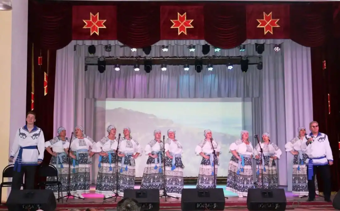 Вокальный коллектив в народных костюмах выступает на сцене Дома культуры.