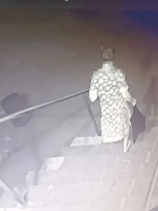 Человек в узорчатой одежде спускается по лестнице с тёмным пакетом.
