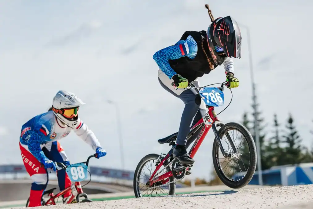 Два спортсмена в шлемах преодолевают подъём на BMX-велосипедах.