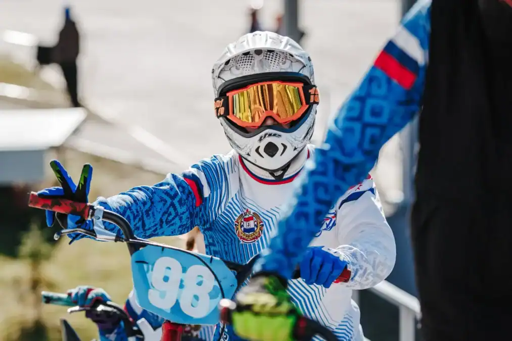 BMX-райдер в защитном шлеме показывает жест рукой, сидя на велосипеде.