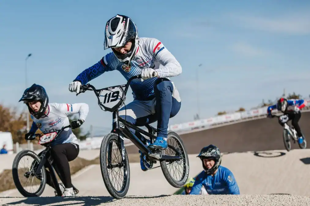 Несколько BMX-райдеров преодолевают трамплин на гоночной трассе.