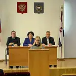Участница заседания выступает за трибуной перед членами президиума.