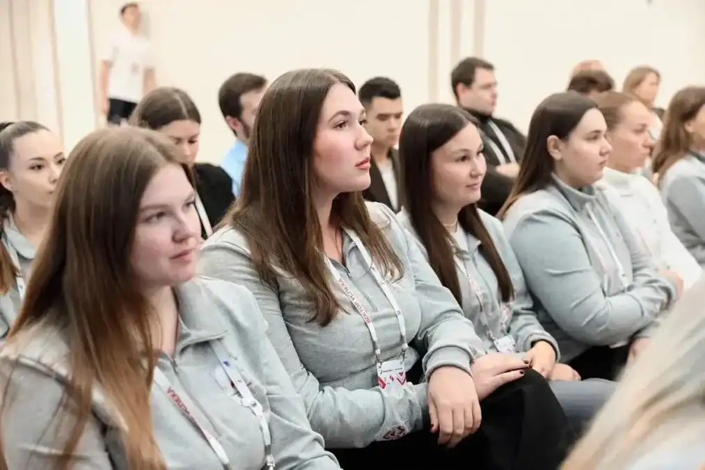 Участники семинара в серых толстовках сидят в зрительном зале.