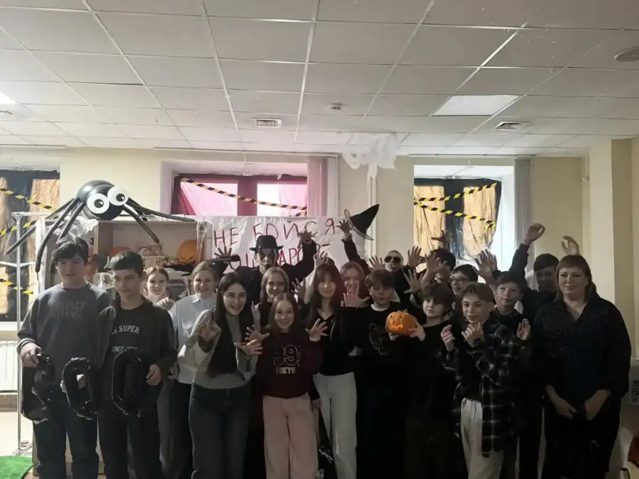 Школьники позируют в украшенном к Хэллоуину холле университета.