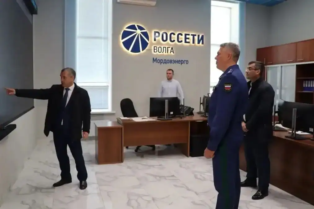 Трое мужчин смотрят на настенный экран в центре управления «Россети Волга Мордовэнерго».