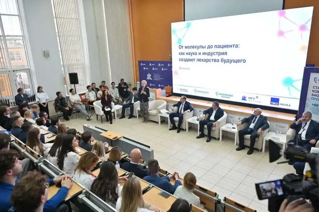 Участники дискуссии сидят на сцене перед аудиторией в университетском зале.