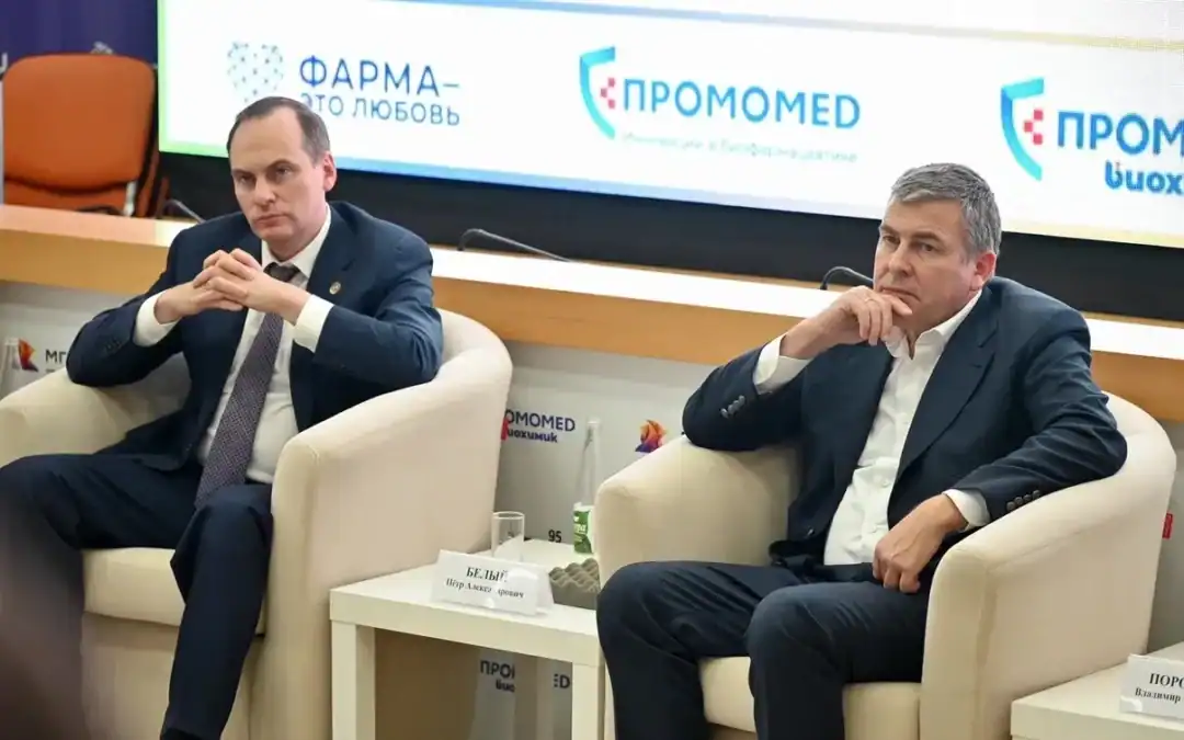 Двое мужчин сидят в креслах на сцене перед баннером «ПРОМОМЕД».