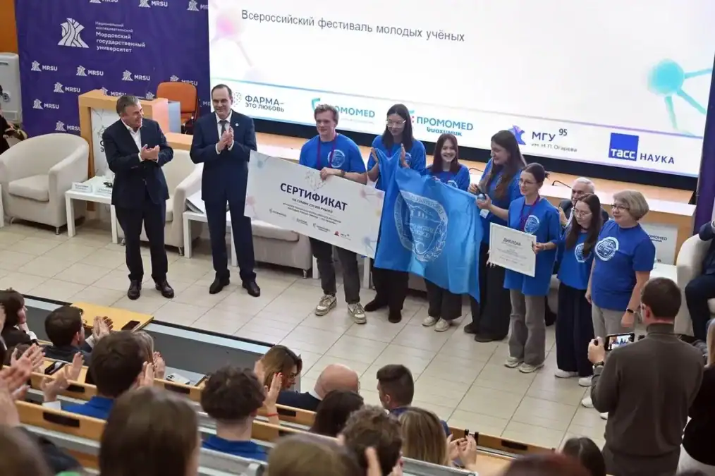 Участники в синих футболках получают сертификаты на сцене фестиваля.