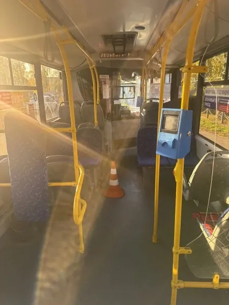 В пустом салоне автобуса в проходе установлен оранжевый сигнальный конус.