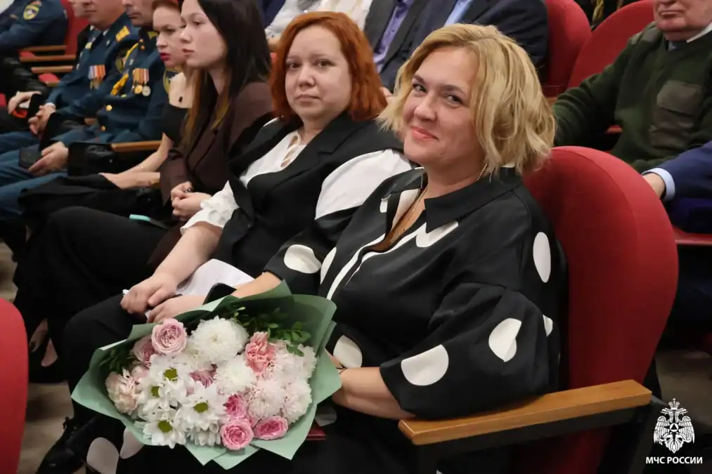 Женщина сидит в зале и держит букет цветов.
