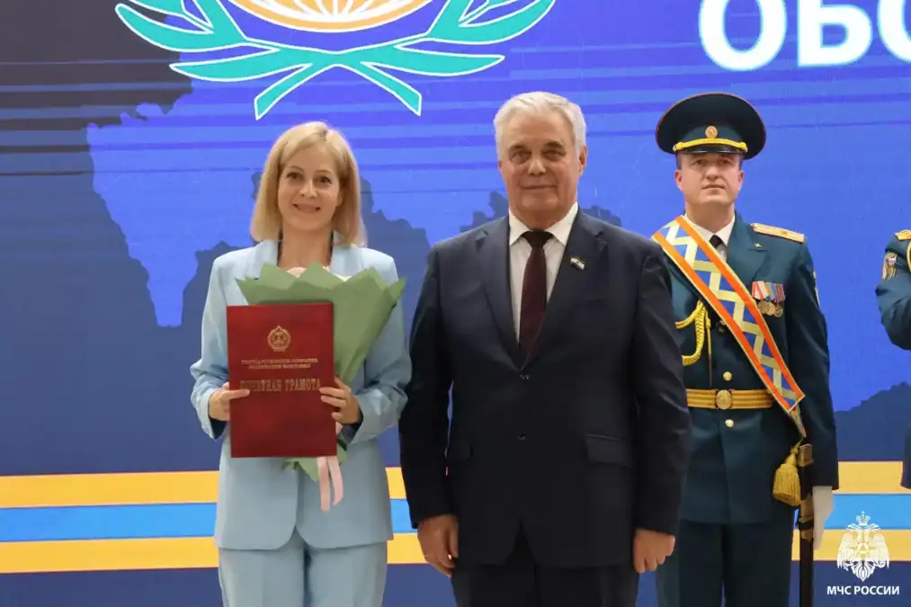 Женщина с букетом и красным наградным документом стоит рядом с мужчиной.