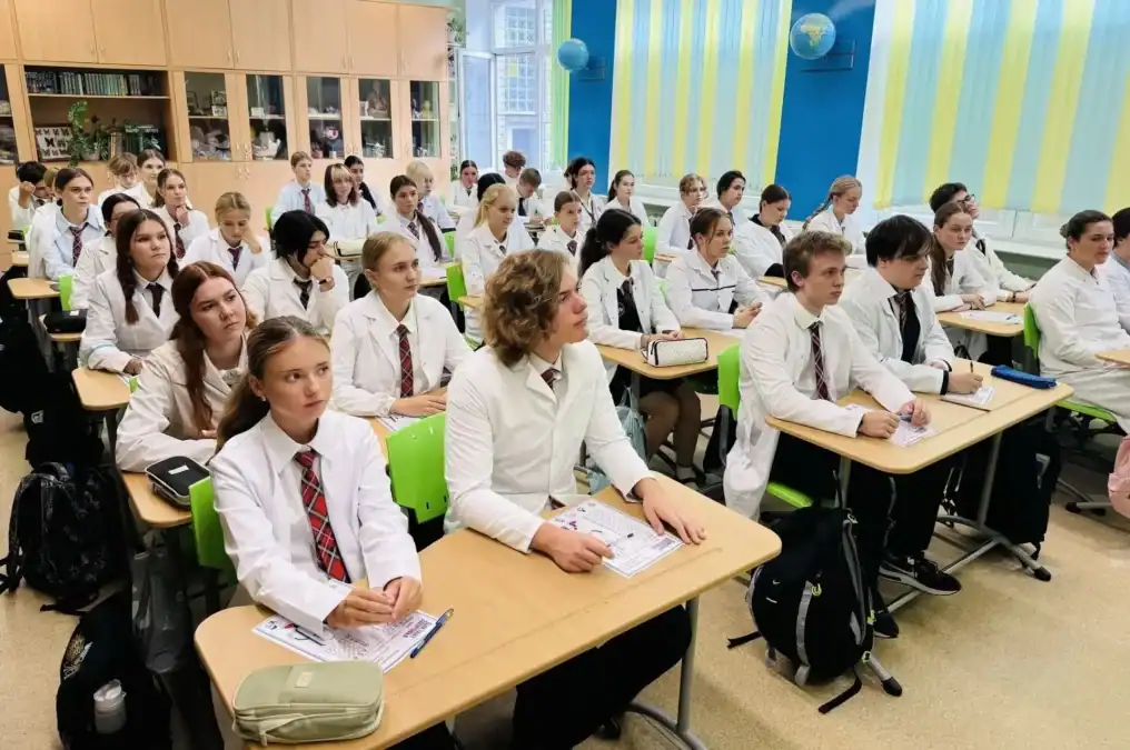 Учащиеся в белых рубашках сидят за партами с бланками заданий.