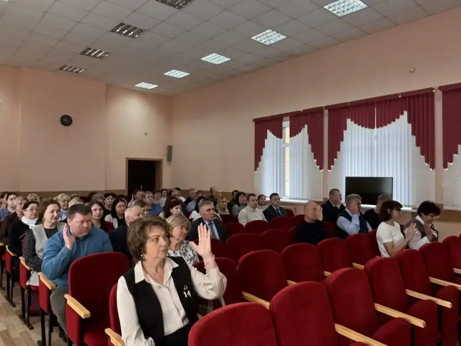 Участники заседания сидят в зале, несколько человек подняли руки для голосования.