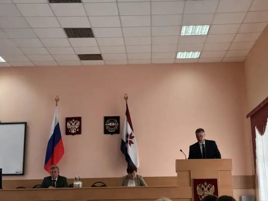 Мужчина выступает с трибуны перед участниками заседания в зале администрации.