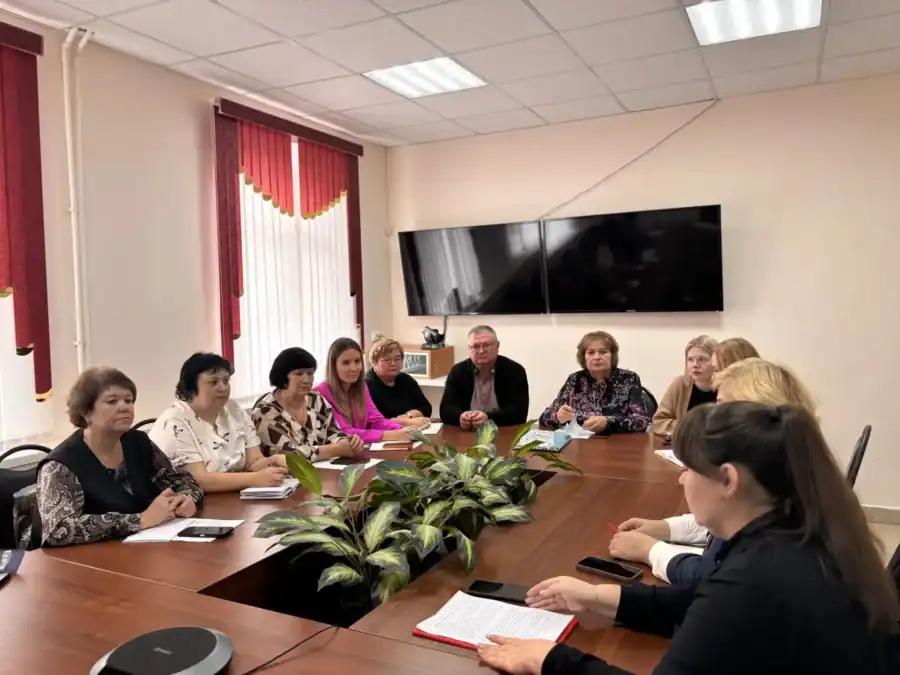 Участники координационного совета обсуждают вопросы за длинным столом в кабинете.