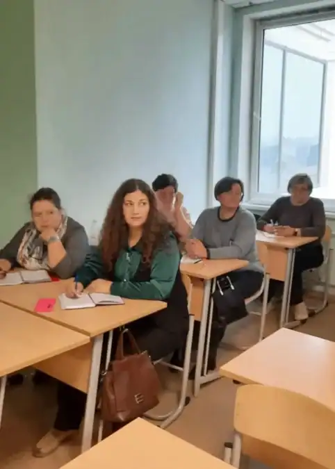 Слушательницы сидят за партами с блокнотами в учебной аудитории.