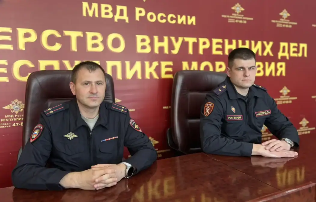 Сотрудники МВД и Росгвардии сидят за столом на фоне пресс-центра МВД Мордовии.