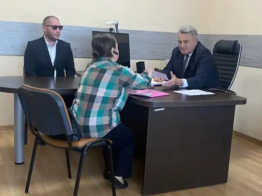 Мужчина в костюме беседует с посетительницей за письменным столом.