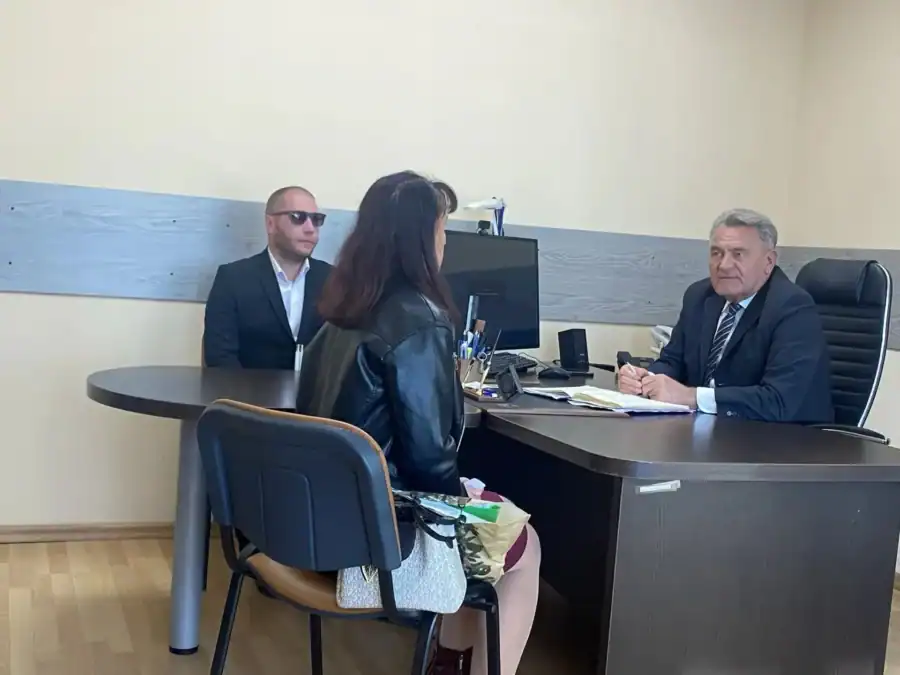 Женщина сидит напротив мужчины в костюме за рабочим столом.