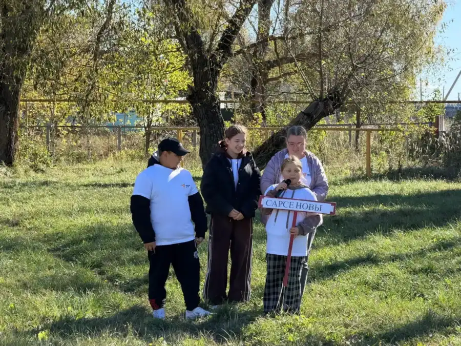 Участники стоят на траве рядом с ребёнком, держащим табличку «Серёжкины».