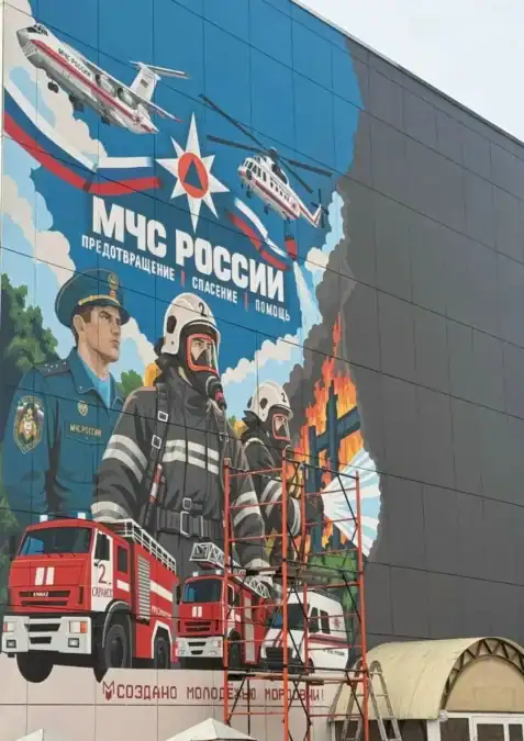 Мурал МЧС с пожарными, техникой и спасательными вертолётами на фасаде здания.