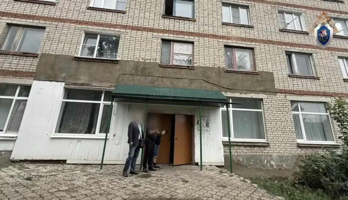 Сотрудники стоят у входа в подъезд многоквартирного дома.